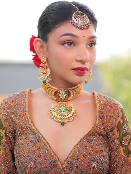 Jewellery is something that has to do with emotion. This model wears a beautiful gold temple-style choker with green accents, perfect for a traditional look.