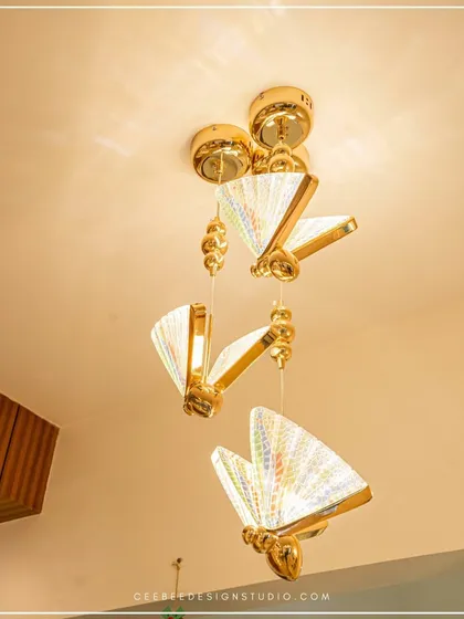 A whimsical butterfly-shaped pendant light fixture with a gold finish.