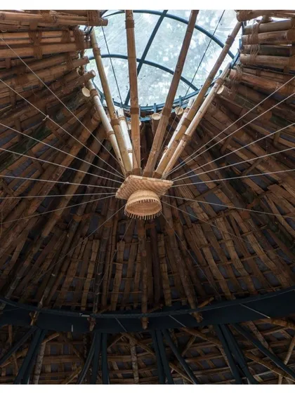A detail of the Koodaaram Pavilion's roof, where bamboo poles converge at a central oculus. This design element fills the space with natural light and creates a stunning visual focus.