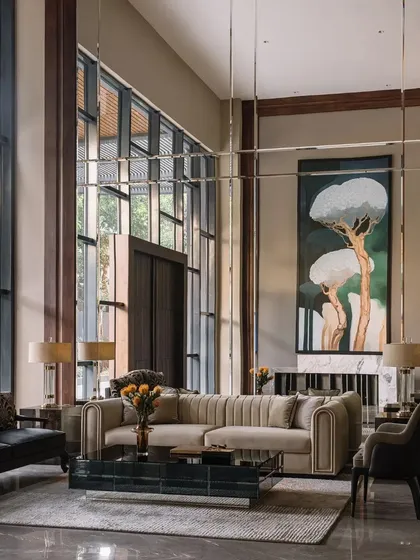 The double-height living room is filled with natural light, with mirrored panels used to enhance the sense of space and reflect the art and garden views.