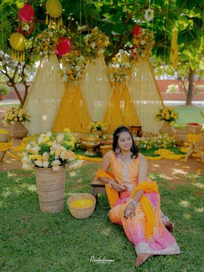 A beautiful solo portrait of the bride at her Haldi ceremony, showcasing her elegant attire and the stunning floral and bamboo decor.