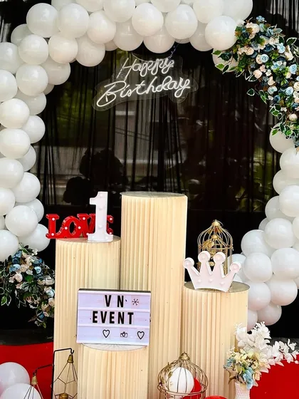 A detailed shot of the white balloon arch, showing the mix of greenery and the placement of the neon sign. We can customize these setups for any theme.