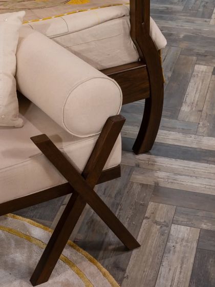 The foot of our bespoke four-poster bed, showcasing the clean lines of the X-frame bench and the beautiful grain of the herringbone wood flooring. These details highlight our commitment to fine craftsmanship and timeless design.