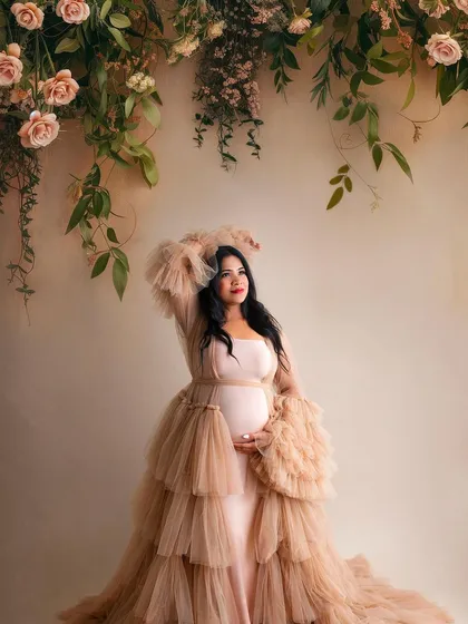 A slightly different pose in the same gorgeous setup. Her looking up towards the flowers adds a touch of whimsy and grace to this beautiful maternity photo.