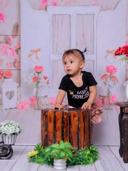 Standing tall like a little princess. This shot captures a milestone moment of the baby supporting herself, framed by the lovely floral backdrop.
