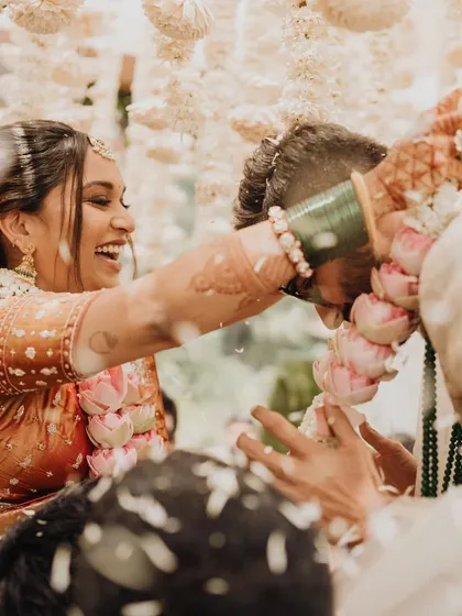 The playful 'varmala war' captured in a moment of pure laughter. These candid shots, set against a backdrop of beautiful floral decor, are often the most cherished.