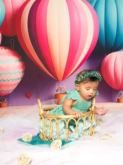 Up, up, and away! A whimsical hot air balloon themed session with a baby girl in a basket, floating among colorful balloons and clouds.