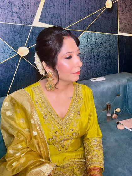 A side profile showing the gajra-wrapped messy bun and the large, traditional jhumkas that complete the look.