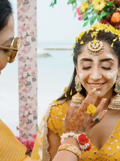 A close-up of the bride's Haldi ceremony, showing the beautiful floral jewelry and the gentle application of turmeric. These details are an important part of the ritual's beauty.