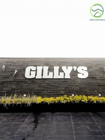 The exterior signage for Gilly's, a commercial project where we used simple, low-lying planters to ground the large sign and add a touch of green to the stone facade.