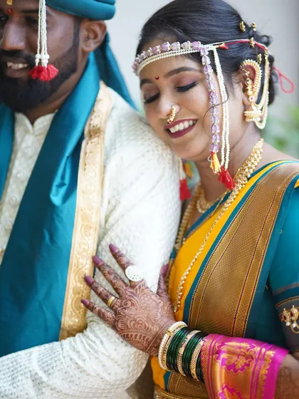 A close-up of the bride's embrace, showcasing her intricate mehndi, green bangles, and the flawless, long-lasting lip color that completes her look.