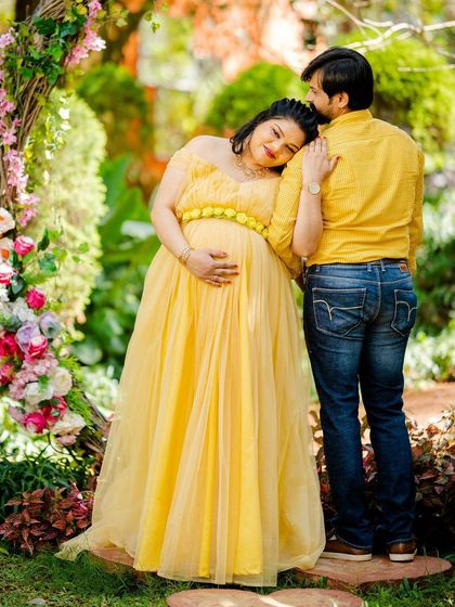 A tender and supportive pose for an expecting couple by the floral arch.