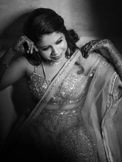A black and white portrait of the bride in her Sangeet lehenga, captured in a quiet moment of reflection in a bathtub for a creative shot.