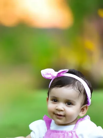 A sweet close up portrait of a baby girl with big brown eyes and a pink bow headband. The soft focus on the background makes her beautiful face the center of attention.