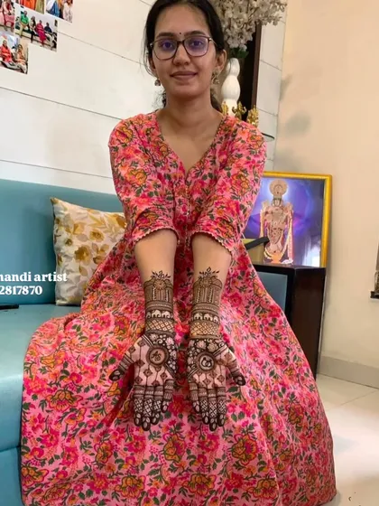 A happy client showing her engagement mehndi, which is a beautiful and balanced design on both palms.