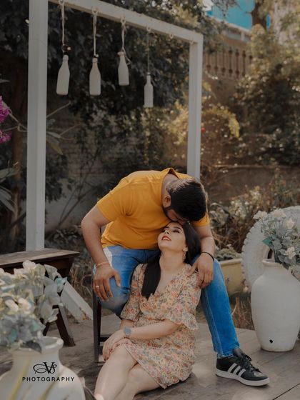 A tender moment captured during a garden pre-wedding shoot, with the groom kissing the bride's forehead in a beautifully decorated setting.