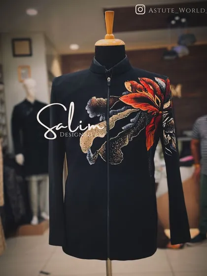 A black Jodhpuri-style jacket with a large, hand-painted floral motif. The vibrant colors of the flower create a beautiful contrast against the dark fabric.