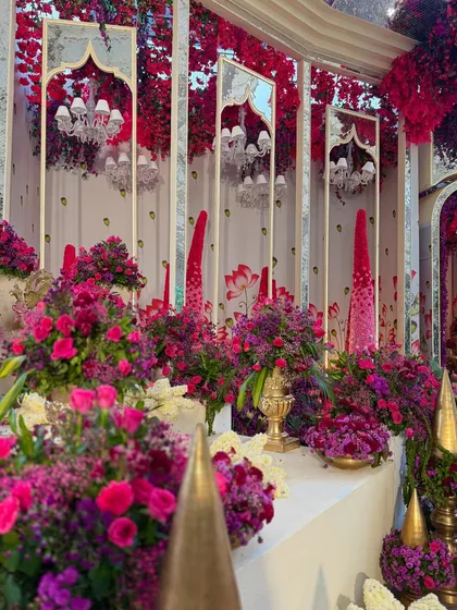 A decor corner filled with an abundance of flowers in bold hues. The mirrored panels and traditional golden elements add layers of luxury and glamour.