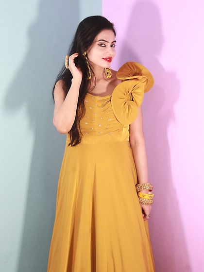 Another pose in the stylish mustard gown, highlighting the unique shoulder design.