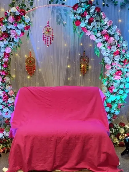 This Roka ceremony setup features a Bohemian touch with dreamcatchers hanging within a large floral ring. The mix of red, pink, and white flowers adds a vibrant pop of color.