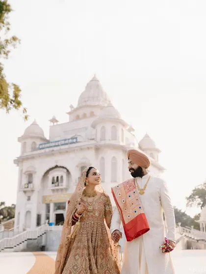 Simranjeet and Bimaljeet walking hand-in-hand outside the pristine white Gurudwara, a perfect blend of love and faith.