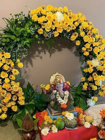 A bright and sunny Ganpati decoration featuring a circular arch of yellow roses and chrysanthemums. This cheerful design is perfect for welcoming Bappa with joy and positivity.