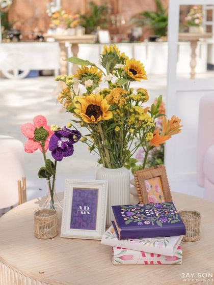 A collection of charming details for the "Bloom" wedding, including custom-designed books, crocheted flowers, and framed art, all contributing to the event's personalized and whimsical theme.