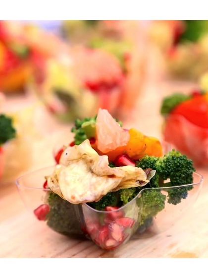 A close up of a healthy and colourful salad cup with broccoli, pomegranate, and citrus. We offer a range of fresh and vibrant options for health conscious guests.