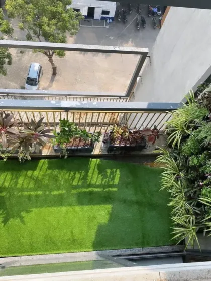This top-down view shows the final result of a balcony transformation, showcasing the lush artificial lawn and the dense greenery of the vertical wall garden.