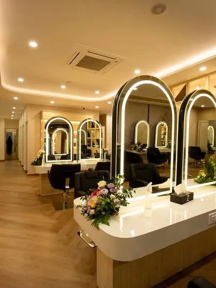 This perspective highlights the salon's spacious layout and the thoughtful arrangement of each workstation. The design ensures easy movement for staff and clients, with consistent design elements like the arched mirrors creating a harmonious visual rhythm throughout the space.