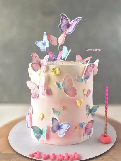 A tall cake covered in a flurry of colourful watercolour-style butterflies, creating a vibrant and artistic effect.