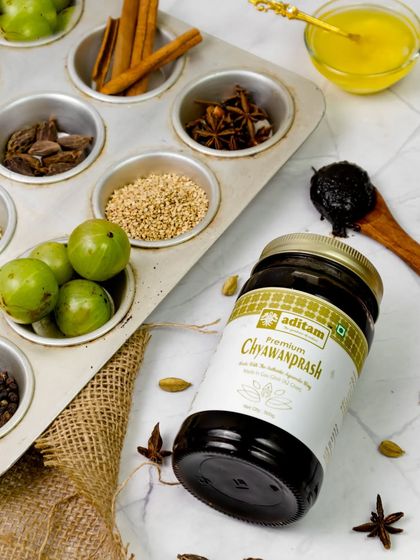 The ingredients of Chyawanprash, such as amla and various spices, are artfully arranged in a muffin tin. This creative flatlay deconstructs the product, showcasing its natural and healthy components.