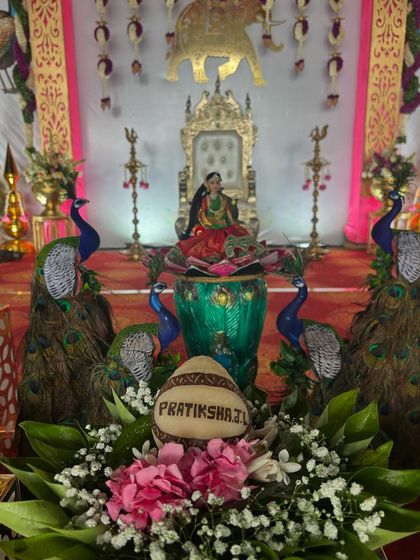 A personalized coconut with the name 'Pratiksha' for a puberty ceremony, surrounded by peacock props.