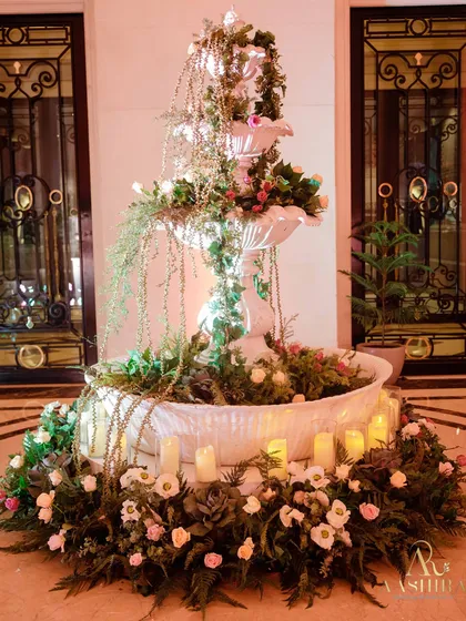 A fairytale welcome. I dressed this fountain in a cascade of white and pink florals, trailing greens, and the warm glow of candles to create a stunning and romantic focal point.