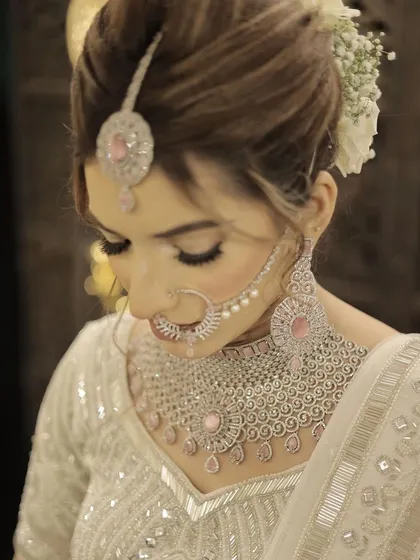 A close-up of the minimalist bride's hair and makeup. The white floral bun and delicate diamond nath complete this modern and sophisticated bridal style.