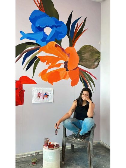 A candid moment of laughter while working on a large, colorful floral mural. Even in moments of intense focus, there is always room for joy in the process.