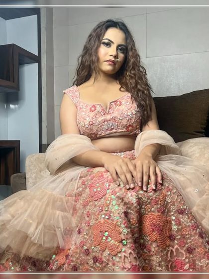 A sitting pose showcasing the beautiful floral sequin work on this peach rental lehenga.