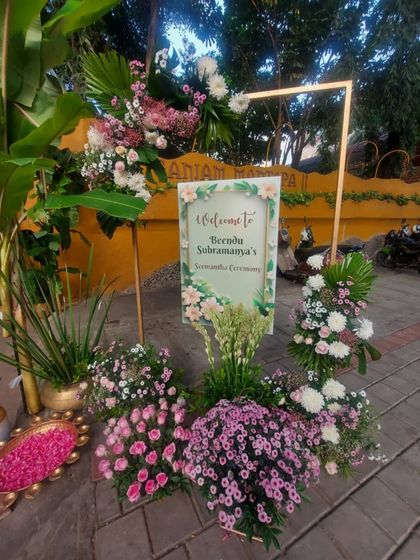A beautiful welcome sign for the Seemantham ceremony, framed with an abundance of fresh pink and white flowers, setting a soft and celebratory tone.