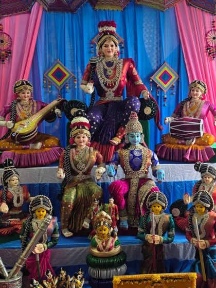 A traditional Golu or doll display set up for a home celebration. It features a variety of handcrafted dolls depicting a divine court scene.