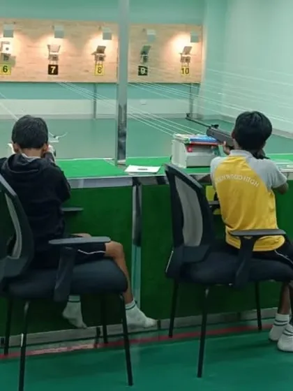 Two young shooters practice side by side, learning from each other in a collaborative environment. Our sessions encourage peer support alongside expert coaching.