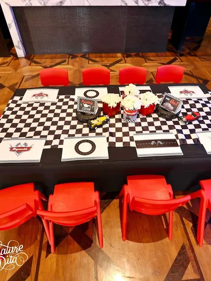 The kids' table at the Cars party, with a checkered tablecloth, bright red chairs, and themed placemats.