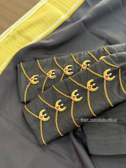 A unique design on a grey blouse with delicate, dangling motifs embroidered on the sleeves.