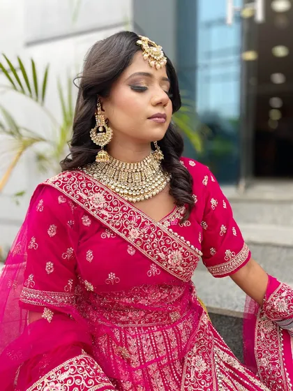 A beautiful bridal look in a vibrant pink lehenga. The student has skillfully balanced a smokey eye with a neutral lip, a key technique for modern bridal makeup.