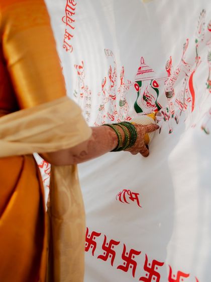 A close-up of a hand pointing to the 'antarpat,' the cloth that separates the bride and groom in a Maharashtrian wedding. A detail shot rich with cultural significance.