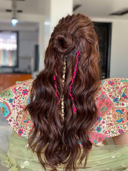 Blooming Mehendi hair. This half-up style features a top knot and colorful thread braids, a fun and bohemian look for a vibrant celebration.