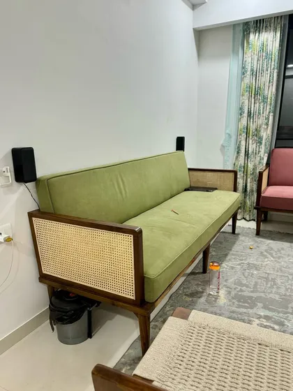 A green upholstered sofa with cane paneling on the arms, part of the same client's set.