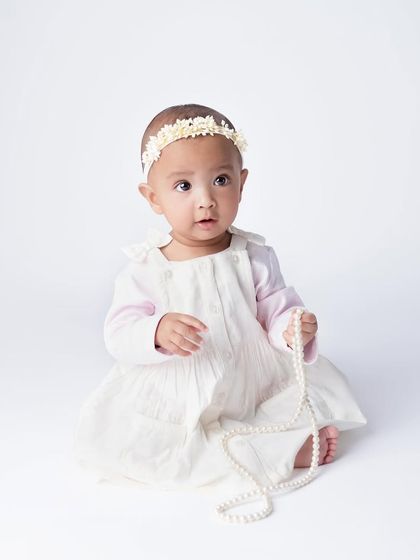 Another take on this classic setup. The baby's curious expression as she holds the pearls is just so precious. These simple portraits are all about capturing personality.