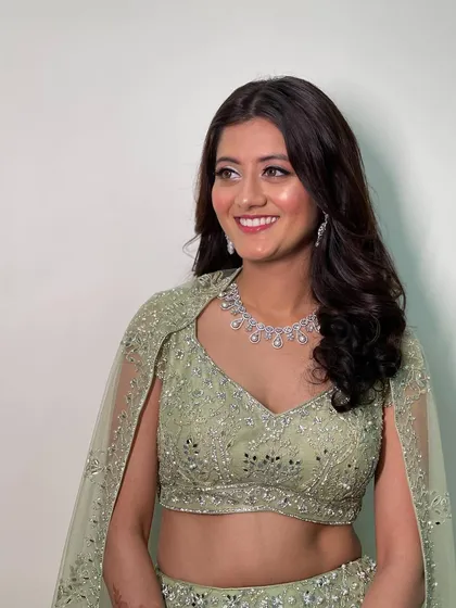 The soft waves are styled to gently frame the face, creating a romantic and effortless look for her engagement celebration.