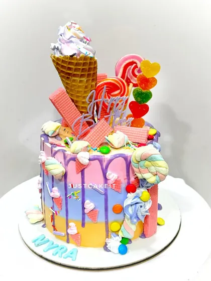This colorful candy theme cake is loaded with treats inside and out. The design features a real ice cream cone, lollipops, and marshmallows, with a mixed fruit flavor inside.