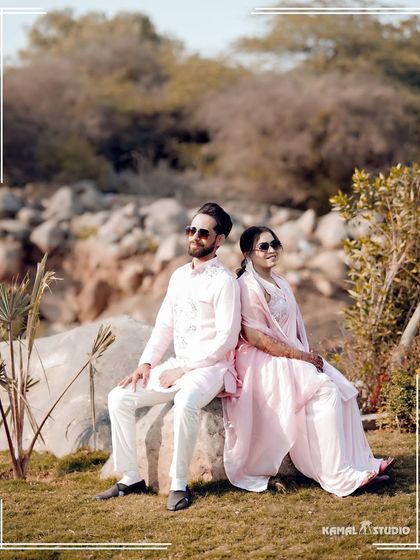 A relaxed and stylish pose during an outdoor Haldi event, with the natural, rocky landscape providing a rustic contrast to the pastel outfits.